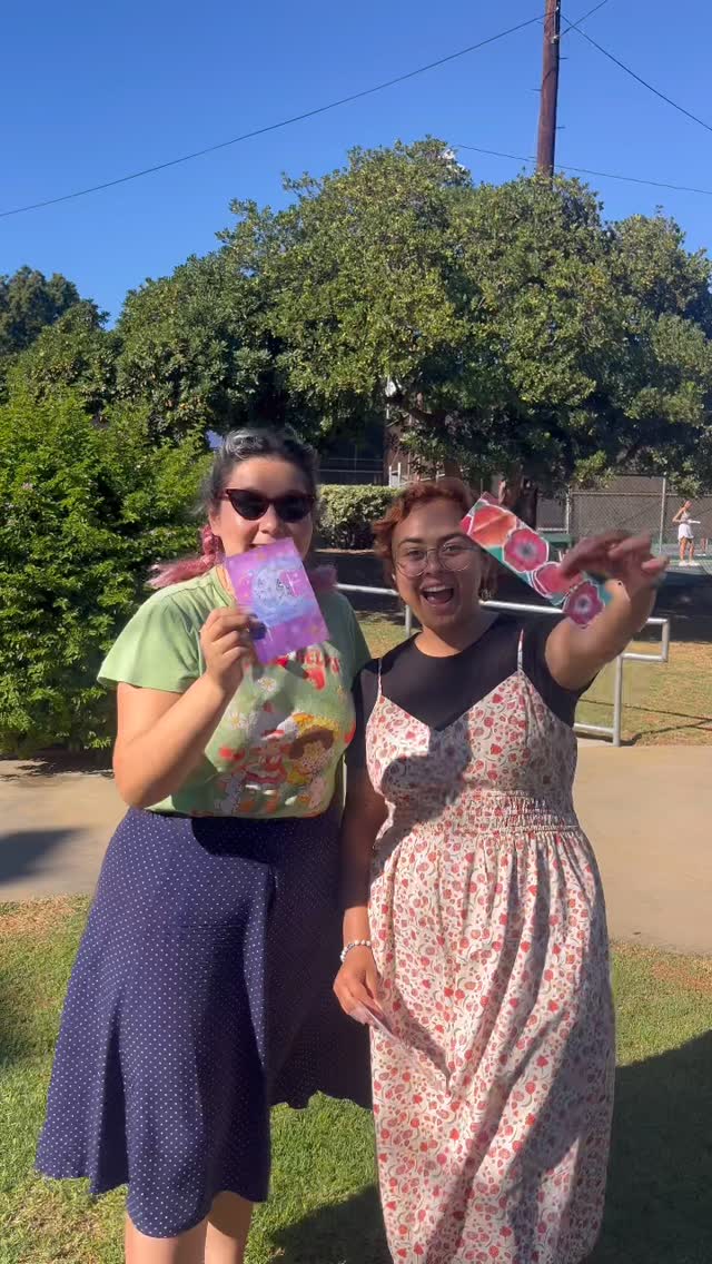 Gaby and friend showing off prints and stickers outdoors